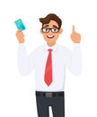 Young businessman holding or showing a credit Debit, ATM card and making or pointing up gesture sign with hand finger. Royalty Free Stock Photo