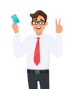 Young businessman holding or showing a credit Debit, ATM card and making victory V, Peace, Two gesture sign with hand finger. Royalty Free Stock Photo