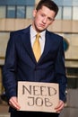 Young businessman holding sign Need Job outdoors