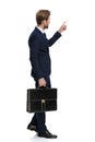 Young businessman holding suitcase and pointing finger to side Royalty Free Stock Photo