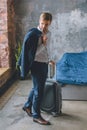 young businessman with jacket over shoulder carrying suitcase in bedroom