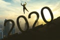 Young businessman jumping above number 2020