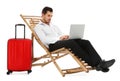 Young businessman with laptop and suitcase on sun lounger against white. Beach accessories Royalty Free Stock Photo