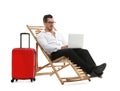 Young businessman with laptop and suitcase on sun lounger against white background Royalty Free Stock Photo