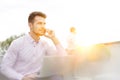 Young businessman with laptop talking on mobile phone in office terrace Royalty Free Stock Photo