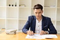 Young Asian businessman looking at market research report. Analyze statistical data in charts. Develop a growth strategy Work on a Royalty Free Stock Photo