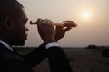 Young businessman looking through telescope in the middle of the desert Royalty Free Stock Photo