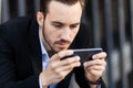 Young businessman looks into phone smartphone, play. Informational dependency