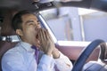 Young businessman looks tired yawning while driving the car Royalty Free Stock Photo