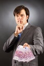 Young businessman making silence gesture and holding euro bankn