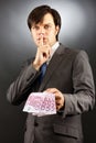 Young businessman making silence gesture and holding euro bankn