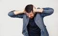 Young businessman man with a beard in a jacket. Hands on head, suffering from headache in despair and under stress due to pain and Royalty Free Stock Photo