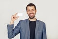 Young businessman man with a beard in a jacket showing a blank sheet of paper. The man smiles and holds in his hand shows a Royalty Free Stock Photo