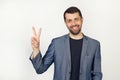 Young businessman man with a beard in a jacket, smiling, looking at the camera, showing thumbs up, making a victory sign. Number Royalty Free Stock Photo