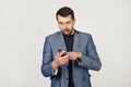 Young businessman man with a beard in a jacket using a smartphone scared shocked with a surprised face, scared and excited with an Royalty Free Stock Photo