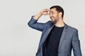 Young businessman man with a beard in a jacket, very happy and smiling, looking far away with hand above his head. Search concept Royalty Free Stock Photo