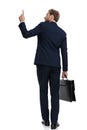 Young businessman in navy blue suit pointing finger and holding suitcase Royalty Free Stock Photo
