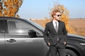 Young businessman near modern car on sunny day