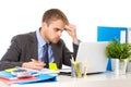 Young businessman overworked looking worried sitting at office computer desk in stress