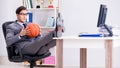 Young businessman playing basketball in office during break Royalty Free Stock Photo