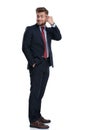 Young businessman pointing to his forehead and holding his hand in his pocket while looking over his shoulder and wearing a blue Royalty Free Stock Photo