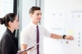Young businessman pointing towards graph and businesswoman holding clipboard with present profit Royalty Free Stock Photo