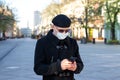 Young businessman with protective mask on face standing alone on empty street.