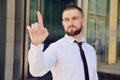 A young businessman pushes his index finger against a virtual screen