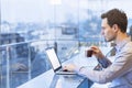 Young businessman reading emails on laptop in modern coffee shop Royalty Free Stock Photo