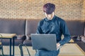 Young businessman reading from a handheld tablet computer with a serious expression as he sits perched on the edge of a table Royalty Free Stock Photo