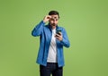 Young businessman reading message over mobile phone with surprise expression over green background Royalty Free Stock Photo