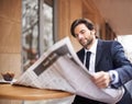 Straight to the business section. A young businessman reading a newspaper outdoors at a coffee shop. Royalty Free Stock Photo