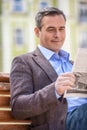 Young businessman reading newspaper while sitting on bench at park. Royalty Free Stock Photo