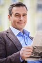 Young businessman reading newspaper while sitting on bench at park Royalty Free Stock Photo