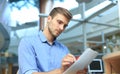 Young businessman reading paperwork at desk in office.