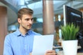 Young businessman reading paperwork at desk in office.