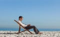 Young businessman resting on his deck chair using his tablet Royalty Free Stock Photo