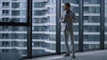 Young businessman searching tablet computer standing by window in office centre.