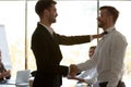 Smiling employer handshake male worker greeting with success