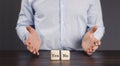 Young businessman in a shirt. Two wooden cubes yes and no. Difficulty of choice concept. On a wooden table