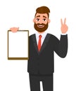 Young businessman showing blank clipboard and making victory, V, peace or two gesture hand sign. Person holding notepad.