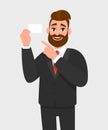Young businessman is showing blank white card and pointing index finger. Person is holding empty card. Male character design. Royalty Free Stock Photo