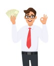 Young businessman showing cash, money and making okay, OK gesture sign with hand fingers. Person holding currency notes. Royalty Free Stock Photo