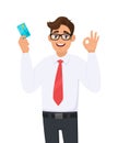 Young businessman showing credit, debit, ATM card and making okay or OK gesture sign with hand fingers. Royalty Free Stock Photo