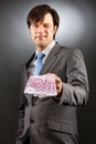 Young businessman showing euro banknotes and winking