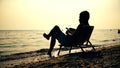 Young businessman silhouette reading a book on beach