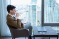 Young businessman sit and relax in the relaxation room by the window overlooking the beautiful city Royalty Free Stock Photo