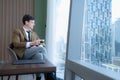 Young businessman sit and relax in the relaxation room by the window overlooking the beautiful city Royalty Free Stock Photo