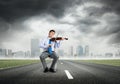 Young businessman sits on the road and plays the violin Royalty Free Stock Photo