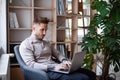 Young businessman sitting in armchair indoors in office, using laptop. Royalty Free Stock Photo